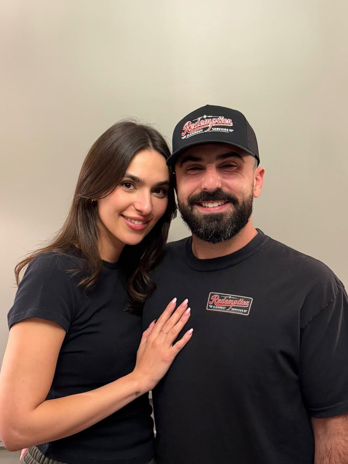 Dante Terracciano and his wife, Laura, smiling together indoors; Dante wears a Redemption Cleanout Services cap and shirt.